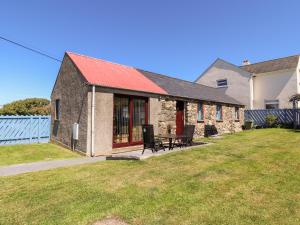 a stone house with a red roof and a yard at Casa Mia in Goodwick
