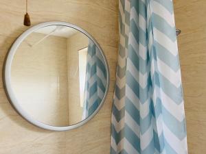 um espelho redondo numa parede com uma cortina de chuveiro em One Bedroom Flat/Apartment. em Bexleyheath