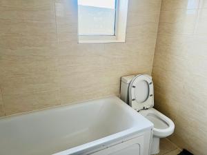 a bathroom with a tub and a toilet and a window at One Bedroom Flat/Apartment. in Bexleyheath