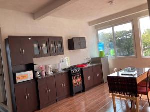 Habitación#1 Casa Rosita a metros del Lago في سان بيدرو لا لاغونا: مطبخ فيه دواليب بنية وموقد