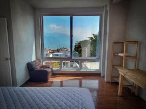 een slaapkamer met een groot raam en een stoel voor een bed bij Habitación#1 Casa Rosita a metros del Lago in San Pedro La Laguna