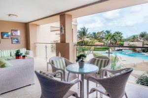 Un balcón con mesa y sillas y una piscina. en The Elegance of Oasis -3BR Apartment Beach Front, en Palm-Eagle Beach
