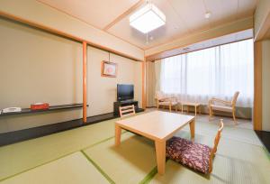 a room with a table and chairs and a tv at 朝里川温泉ホテル in Otaru