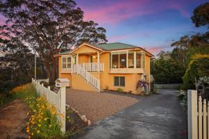 uma casa amarela com uma cerca em frente em Cliff Haven Retreat em Katoomba