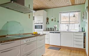 a kitchen with white cabinets and a window at Holiday Home Klintevej Faxe Ladeplads Ii in Fakse Ladeplads
