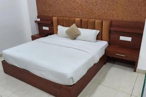 a bedroom with a large bed with a wooden headboard at Hotel Ganga Amrit Haridwar Near Railway Station in Haridwār