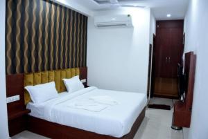 sypialnia z białym łóżkiem z drewnianym zagłówkiem w obiekcie Hotel Ganga Amrit Haridwar Near Railway Station w mieście Haridwar