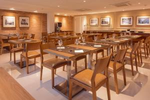 a restaurant with wooden tables and chairs at Intercity Salvador Aeroporto in Lauro de Freitas