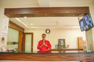 a man is standing in front of a counter with his hands at Hotel Sachidanand in Shirdi