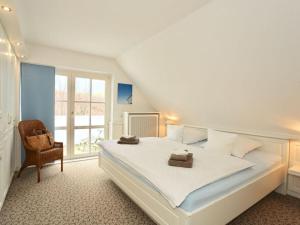 1 dormitorio con 1 cama blanca grande y 1 silla en Strandhuus Modern retreat, en Juist