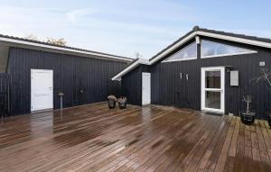 a black house with a wooden floor and a deck at Awesome Home In Juelsminde With Wifi in Sønderby +21 photos