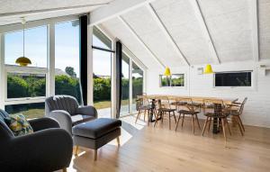 a living room with a table and chairs and windows at Awesome Home In Juelsminde With House Sea View in Juelsminde