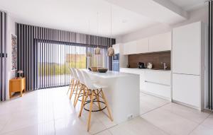 a kitchen with white cabinets and a table and chairs at 3 Bedroom Amazing Home In Allauch in Allauch