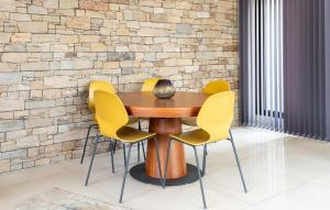 a wooden table with yellow chairs in front of a brick wall at 3 Bedroom Amazing Home In Allauch in Allauch