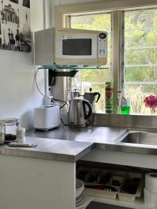 uma cozinha com pia e micro-ondas em Rustic, Basic Cosy Alpine Hut, in the middle of the Mountains em Otira