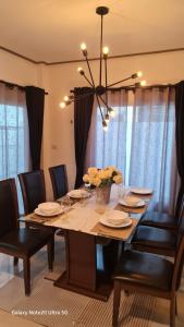 een eettafel met zwarte stoelen en een kroonluchter bij 3bed3room in Ban Rangeng
