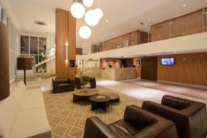 En un edificio hay una sala de estar con sofás y TV. en Intercity Salvador Aeroporto, en Lauro de Freitas