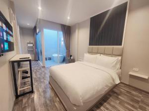 a bedroom with a large white bed and a bathroom at Skyline Resort in Ban Khlong Lat Bua Khao