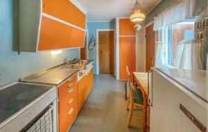 OsにあるGorgeous Home In Os I Østerdalenのキッチン(オレンジ色のキャビネット、シンク、テーブル付)