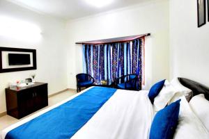 Un dormitorio con una cama azul y blanca y una ventana en Hotel Silver Tree IVY The Boutique - Luxury Stay - Excellent Service - Parking Facilities en Bhīm Tāl