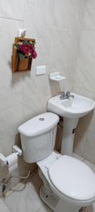 a white bathroom with a toilet and a sink at Departamento Riobamba in Riobamba