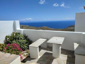 a bench sitting next to a white wall with the ocean at ANATOLI ROOMS SERIFOS in Serifos Chora