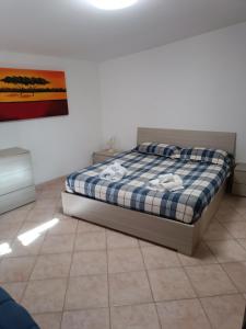 a bedroom with a bed with a blue and white plaid at Villino fiera di Roma e aeroporto Fiumicino in Ponte Galeria