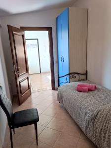 ein Schlafzimmer mit einem Bett, einem Stuhl und einer Tür in der Unterkunft Villino fiera di Roma e aeroporto Fiumicino in Ponte Galeria
