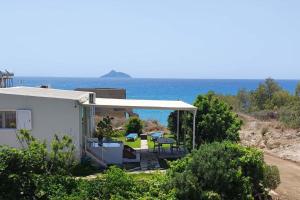 ein weißes Haus mit einer Terrasse mit Meerblick im Hintergrund in der Unterkunft Bungalow Thalassa, am Strand und mit Mini-Pool in Kalamaki
