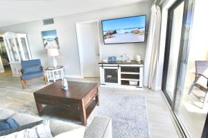 a living room with a couch and a tv on the wall at Ocean Breeze Condo in Jensen Beach