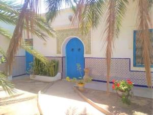 a building with a blue door and palm trees at Dar Rita in Houmt Souk