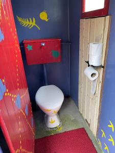 een kleine badkamer met een toilet en een deur bij Rustic, Basic Cosy Alpine Hut, in the middle of the Mountains in Otira