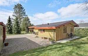 a small yellow house with a patio and grass at Beautiful Home In Frvang With Sauna in Fårvang