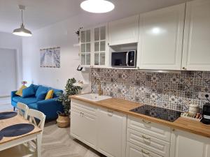 a kitchen with white cabinets and a blue couch at Blue Promenade Apartments in Dubrovnik