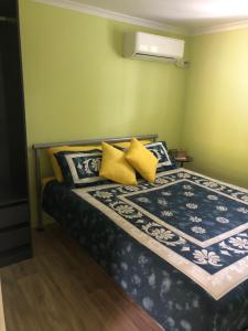 1 dormitorio con 1 cama con almohadas amarillas y azules en Curra Cottage en Curra