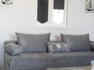 a gray couch with pillows in a living room at Splendid Santorini Villa | Bella Beach House | 3 Bedrooms | Private Terrace and Beautiful Sea Views | Monolithos in Monolithos