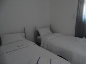 two beds in a small room with white sheets at Splendid Santorini Villa | Bella Beach House | 3 Bedrooms | Private Terrace and Beautiful Sea Views | Monolithos in Monolithos