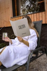 Ein Mädchen, das auf einem Stuhl sitzt und ein Buch liest. in der Unterkunft Golden Golem hotel & Spa in Prag