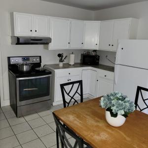 een keuken met witte kasten, een tafel en een koelkast bij Entire 4 bedroom house - Enfield in Enfield