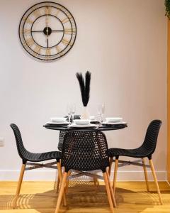 TQ luxurious 2 bed flat في برمنغهام: طاولة طعام مع كراسي وساعة على الحائط