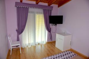 een woonkamer met paarse gordijnen en een tv bij Hotel & Restaurant White City in Berat