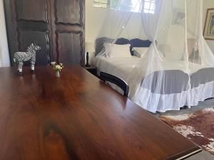 a room with a wooden table and a bed with a zebra statue at Kruger Park Farmstay near Orpen Gate in Hoedspruit +37 photos