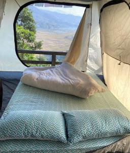 uma cama na parte de trás de uma tenda com uma janela em Back To Nature em Pokhara