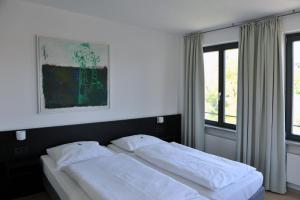two twin beds in a room with two windows at Tandem Hotel in Bamberg