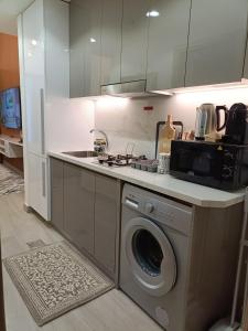 a kitchen with a sink and a washing machine at Luxury Staycation Studio in Royal Neighbourhood in Dubai