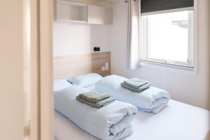 two beds in a white room with towels on them at Magnolia - Camping Belle-Vue in Berdorf