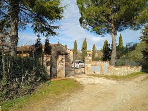 a gate to a house with a car in the driveway at Villetta con parco vicino San Gimignano in Le Grazie