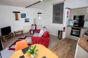 uma sala de estar com um sofá vermelho e uma televisão em Treworgie Barton - Butterwell em Bude