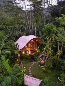 a small hut in the middle of a garden at Arcada Bali Bamboo House in Sidemen