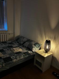a bedroom with a bed and a lamp on a night stand at Apartament dla Ciebie in Kętrzyn